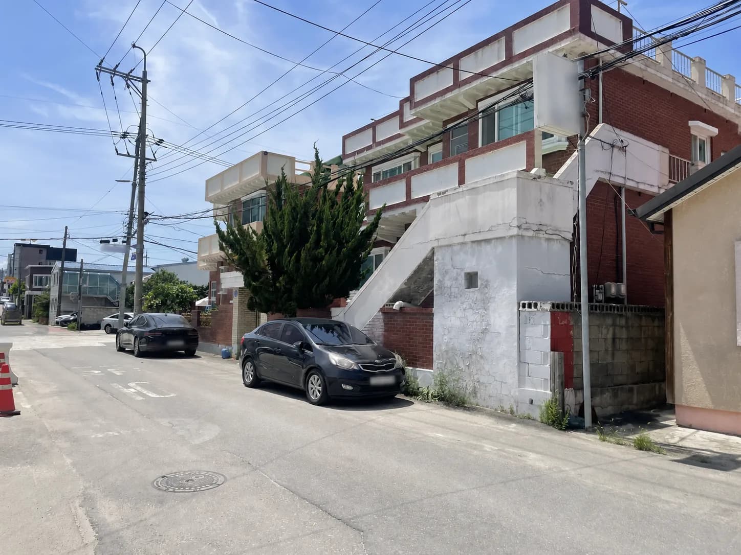 골목에서 바라본 외부 계단과 테라스가 있는 2층 건물