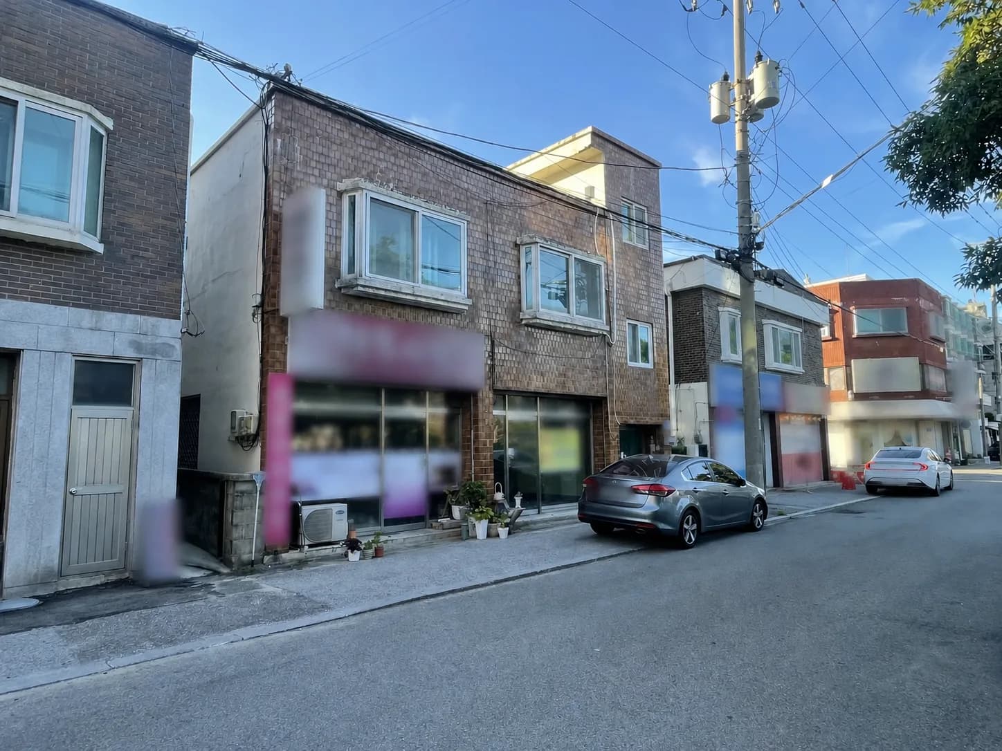 골목에서 비스듬히 바라본 벽돌 상가와 주변 도로